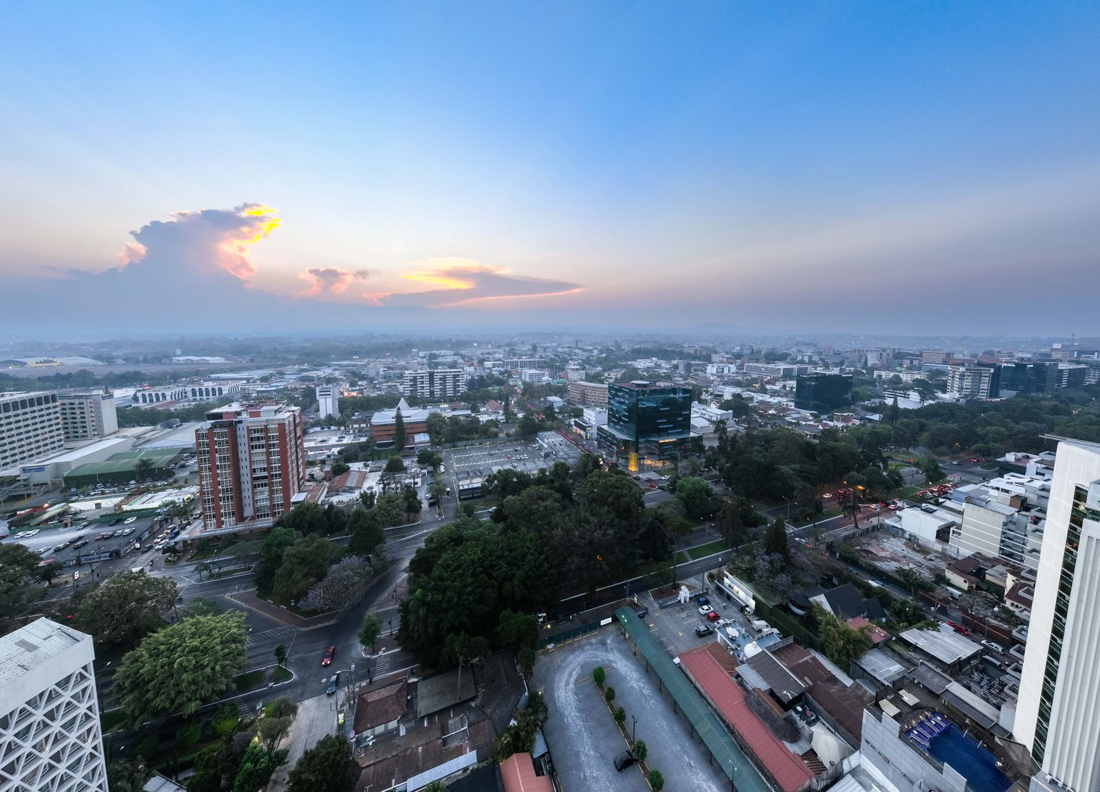 Panoramic aerial view of Guatemala City during sunset, showcasing urban landscape and skyline.