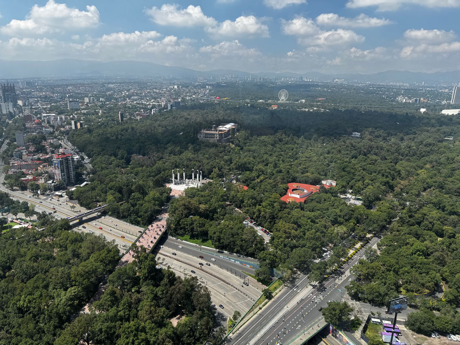 A stunning aerial view of Chapultepec Park with cityscape and mountains in the background.