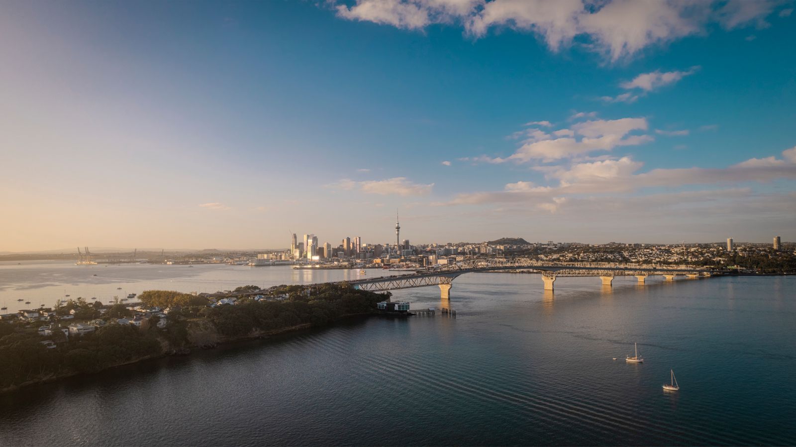 Stunning aerial view of Auckland city skyline and Harbor Bridge at sunset.