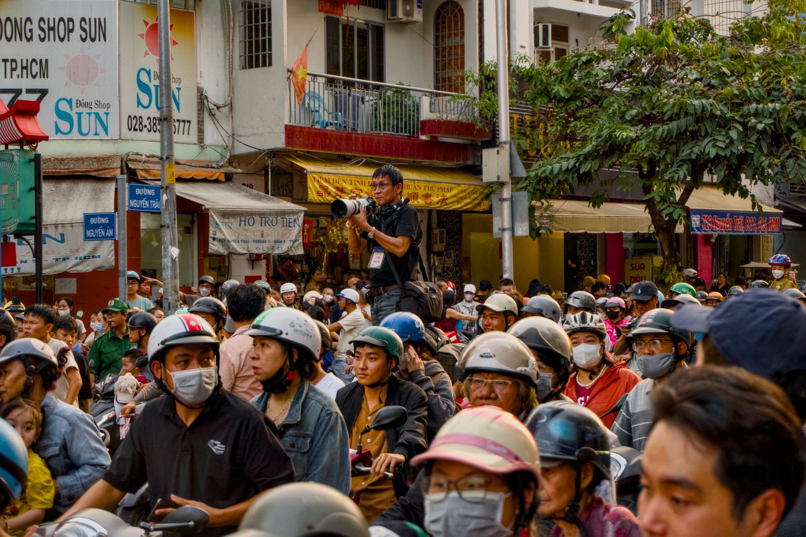 A bustling street packed with people and a photographer taking pictures.